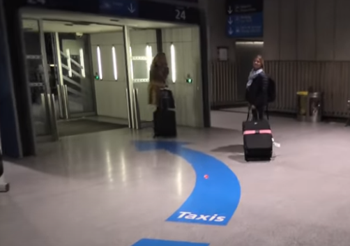 Lady pulling suitcase towards  gate at Charles de Gaulle airport to take a taxi